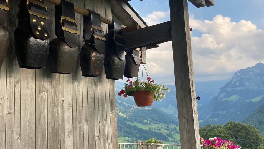 Glocken hängen am Bauernhaus mit Sicht auf Berge im Hintergrund